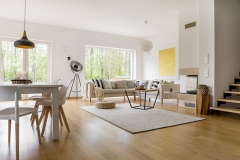 Beige sofa with pillows in multifunctional living room with dining table and white chairs